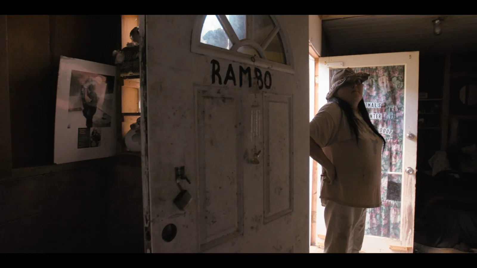 A woman in a cowgirl hat stands in a doorway.