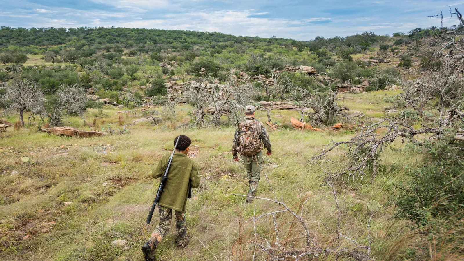 Two Kids trapse Texas back country forest with rifles.