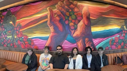 Rubio sits with his students in front of a mural they created.
